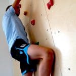 Kind trainiert motorische Fähigkeiten an einer Kletterwand